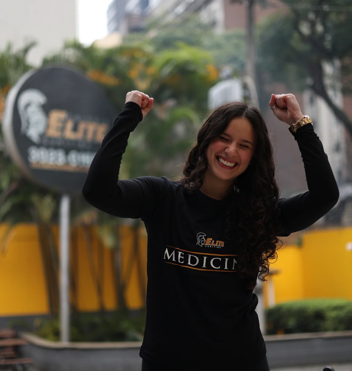 Aluna do Elite comemorando em frente a uma das unidades